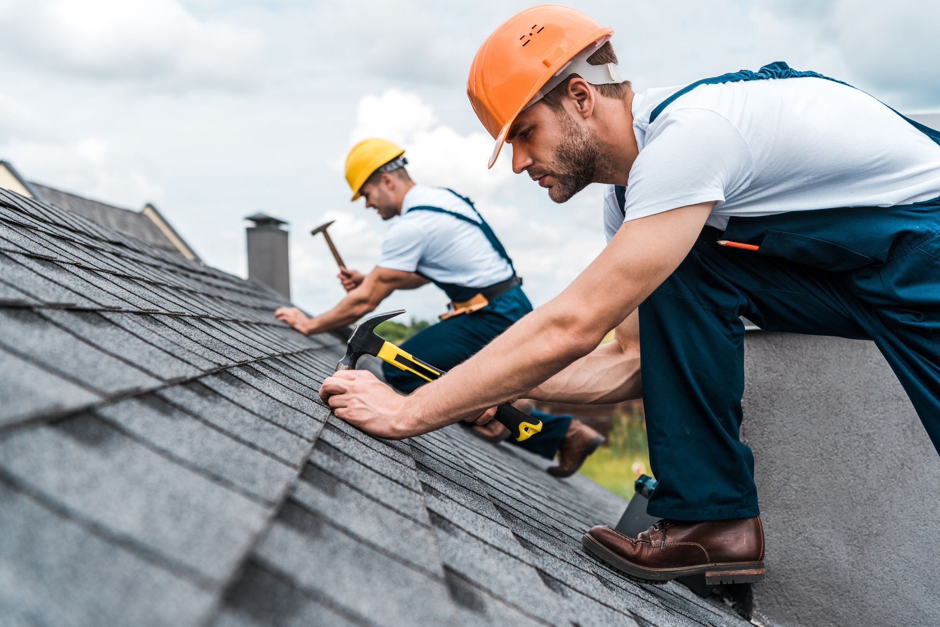 Two roofers securing shingles during a residential repair.